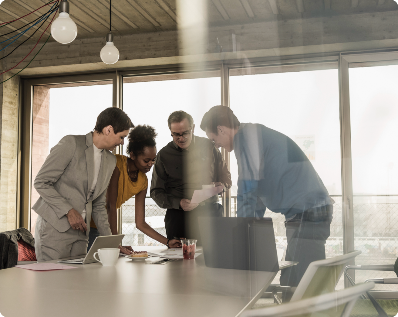 A group of people gather to look at a document in a sunny conference room