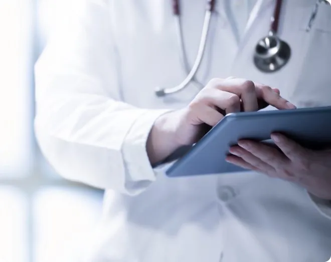 A doctor wearing a stethoscope, working on a tablet.