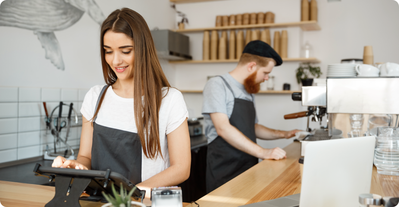 Two baristas working behind the counter of a coffee shop.