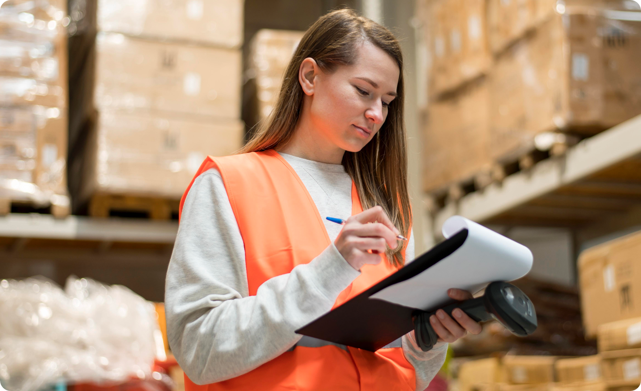 A warehouse worker checks a document on a clipboard