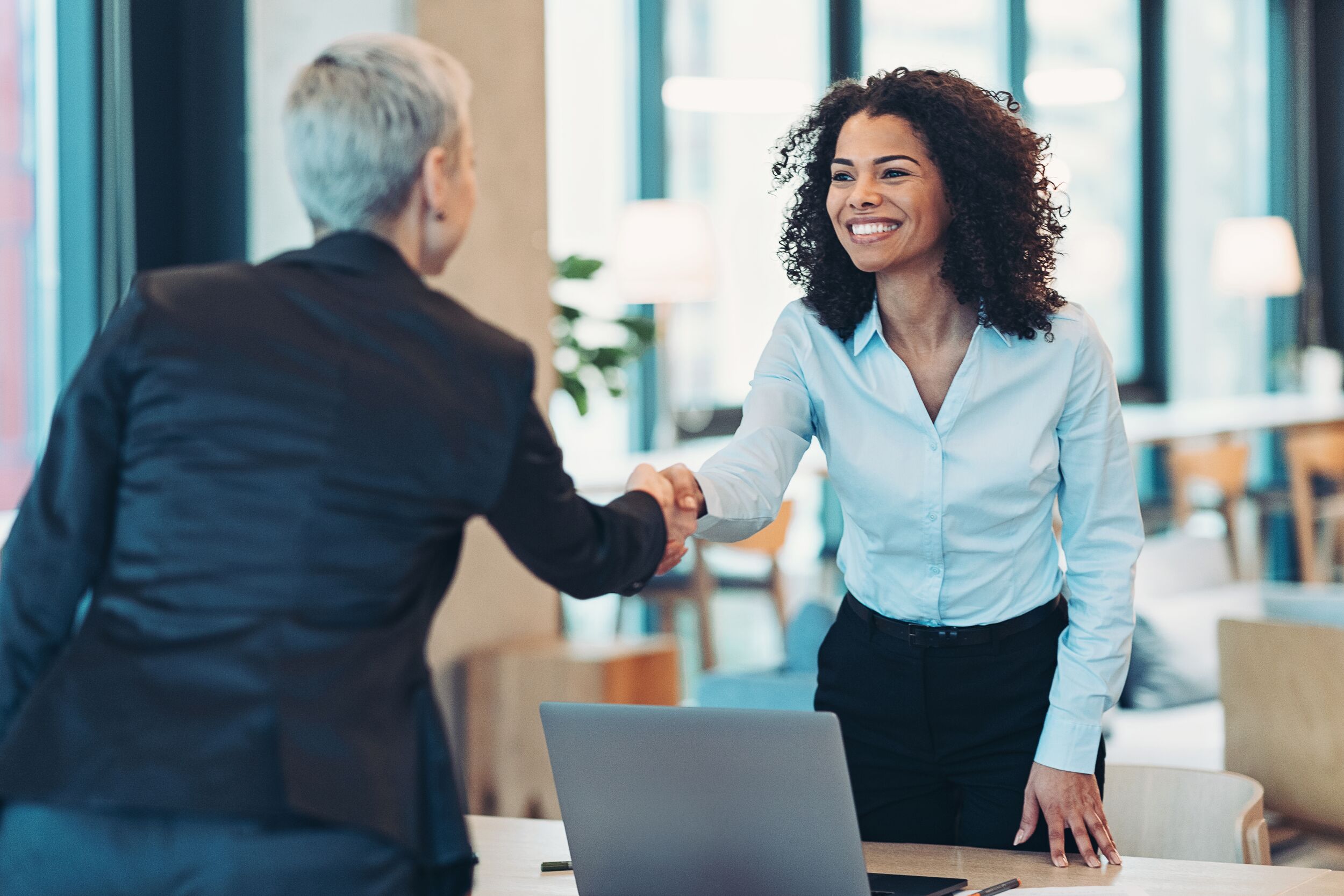 Two business women shaking hands.