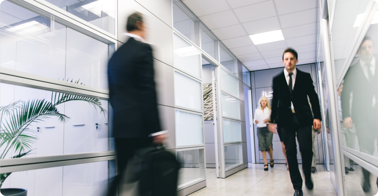 A man in a suit rushes down a hallway
