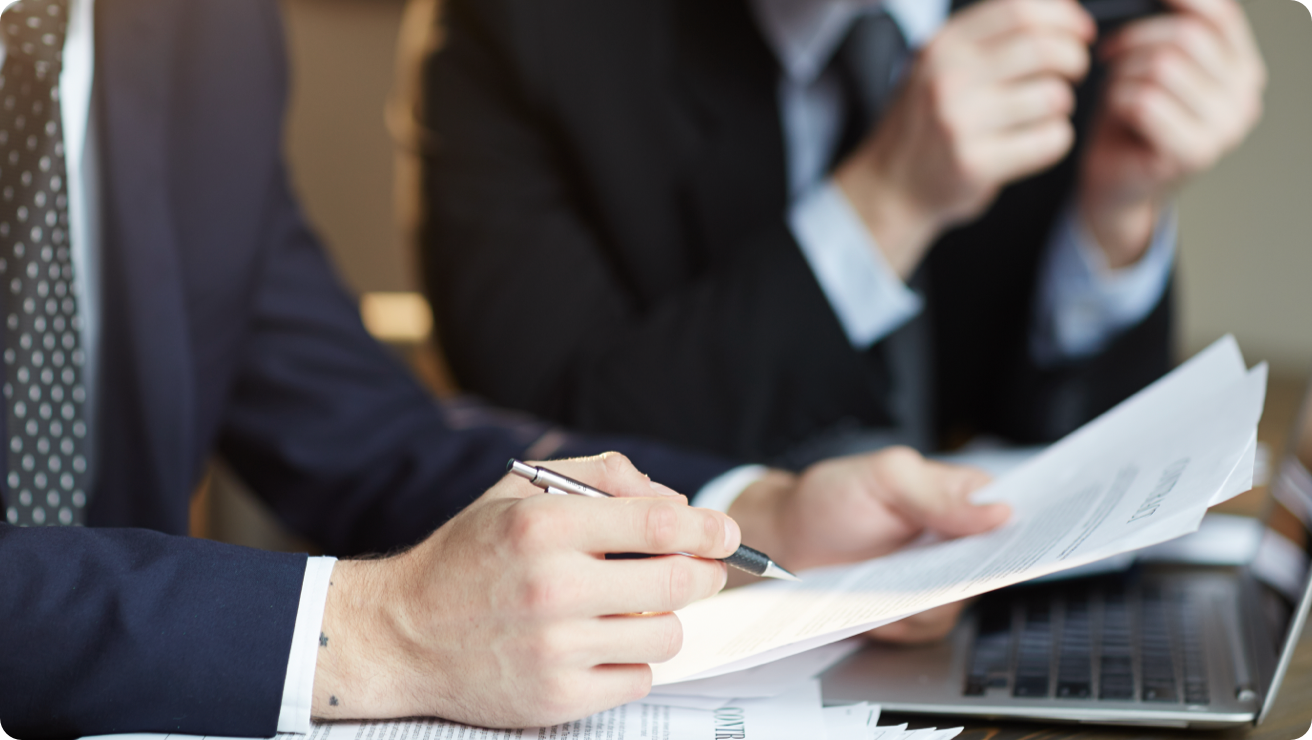 A person holds a pen up to a document as they study it.