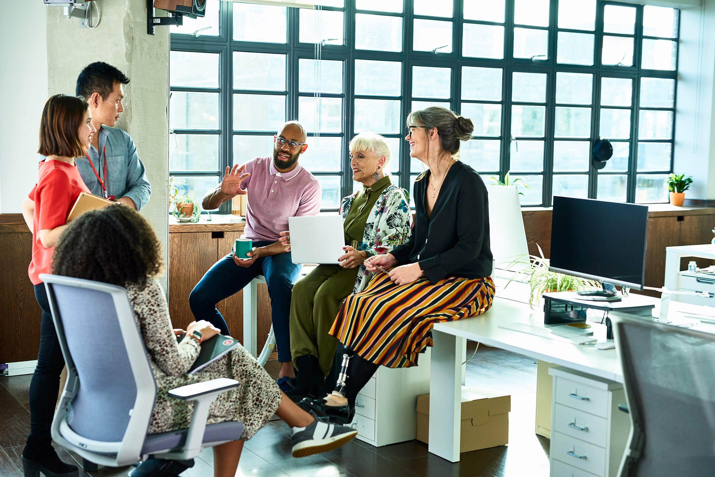 Six people sitting around a desk talking
