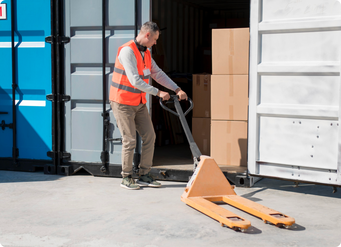 A worker wheels a dolly up to a storage container
